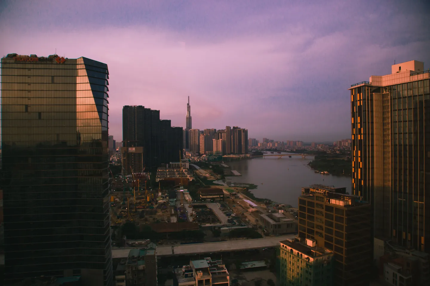 Ho Chi Minh City skyline at golden hour, with Landmark 81 rising above the Saigon River between two glass office towers