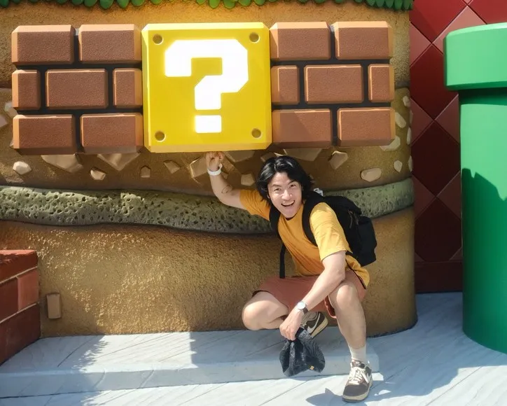 Joey crouching under a Super Mario question block, one hand raised to punch it